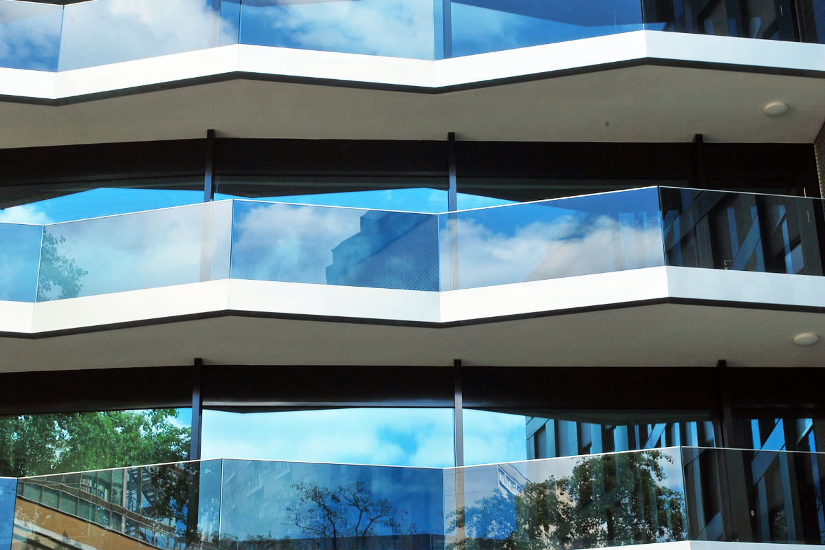 Edificio residencial con balcones de vidrio protegido con películas arquitectónicas de control solar para mejorar el confort y la eficiencia energética.