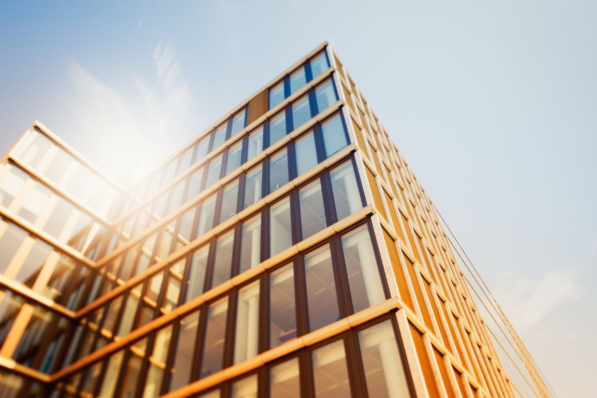 Edificio corporativo con fachada de vidrio expuesta a la radiación solar, donde la orientación de las ventanas influye en la elección de la película arquitectónica de control solar.