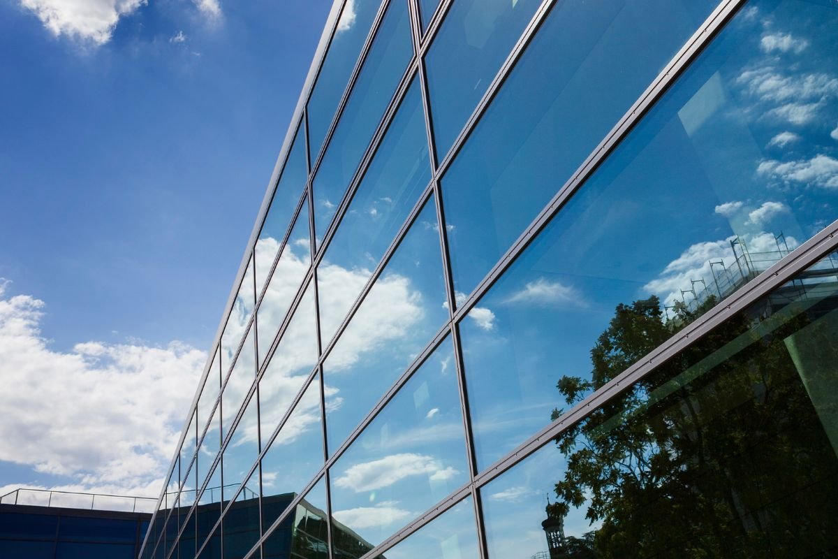 Instalación de película de seguridad arquitectónica en fachada de edificio para reforzar la resistencia del vidrio y mejorar la protección estructural.