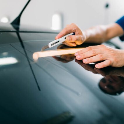 Técnico utilizando cuchilla para cortar película polarizada durante instalación.